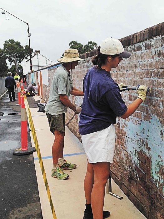 Stripping the wall for restoring the 40,000 Years mural at Redfern station Photo: Lyn Turnbull